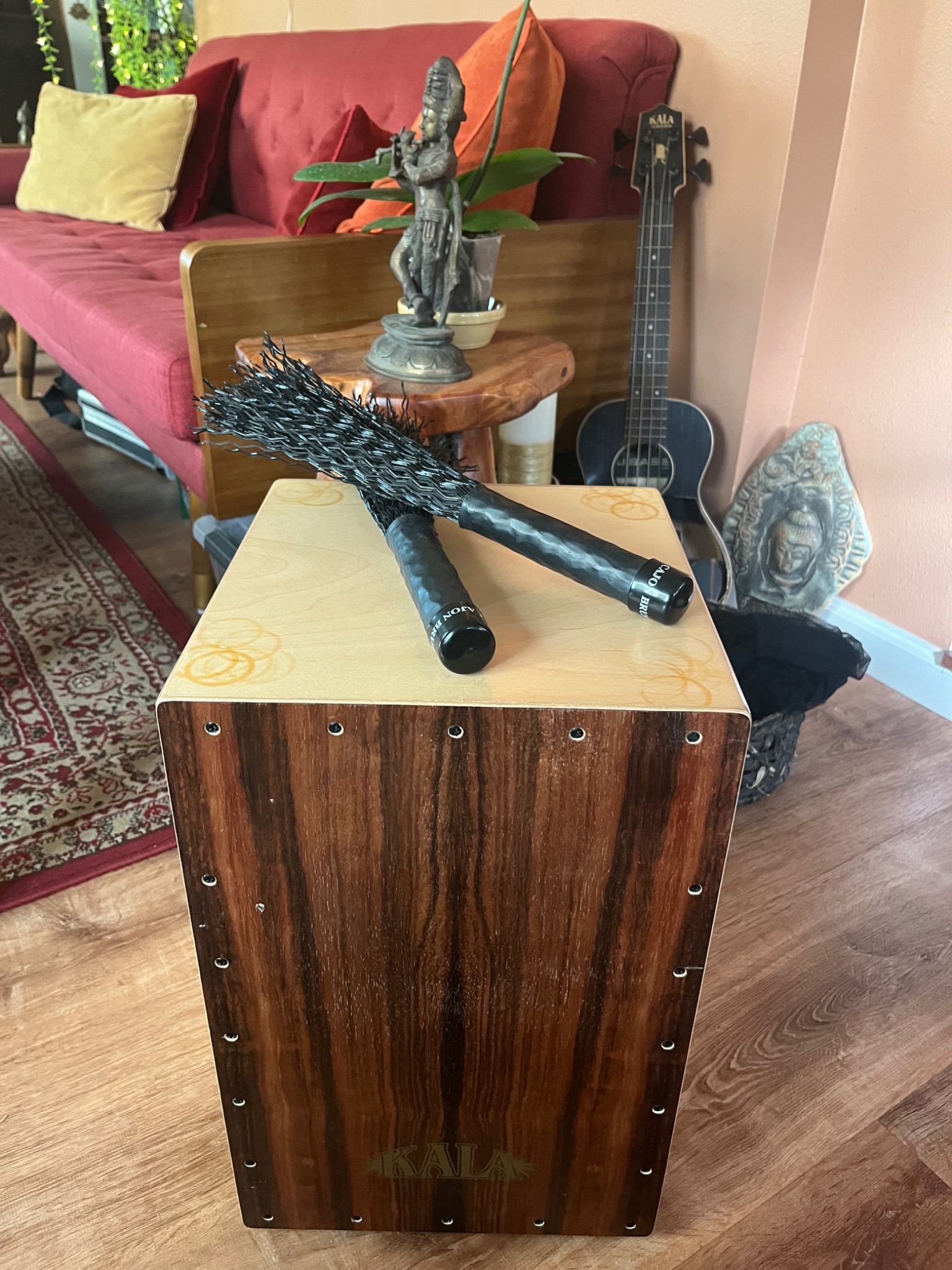 A cajón and microphones beside the comfortable red studio sofa